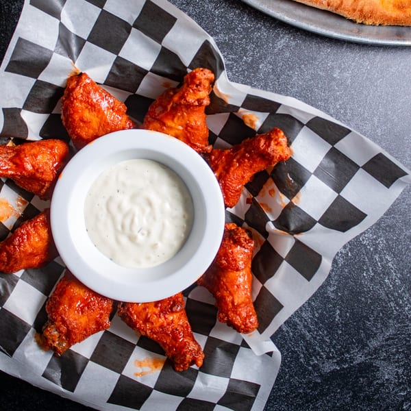 Mr. G's Italian Pizzeria's buffalo wings with ranch dressing on checkered paper.