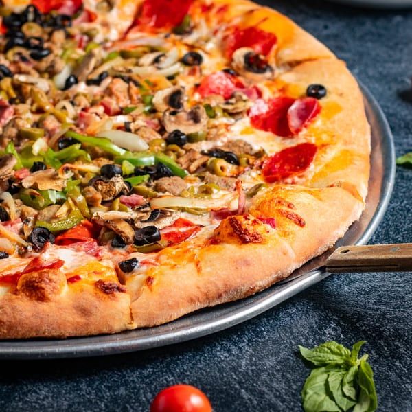 Close-up of a Mr. G's Italian Pizzeria pizza with pepperoni, mushrooms, olives, and peppers.